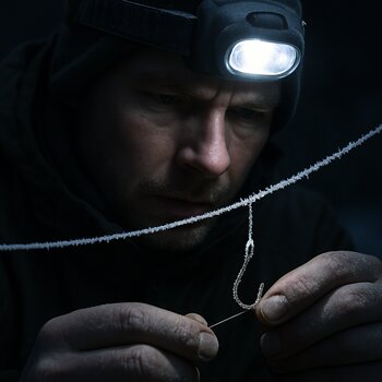 Headlamp beam lighting frosted fishing line over a hole